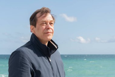 Deniz ve gökyüzüne karşı ceketli yaşlı bir adam..