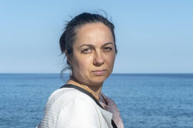 Denizin arka planında 40-45 yaşlarında bir kadının duygusal portresi..