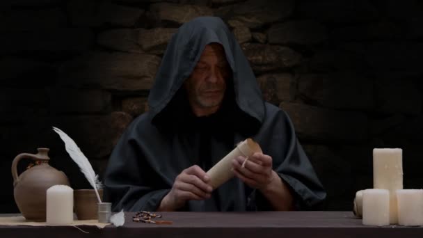 Velho Monge Abre Pergaminho Sentado Uma Mesa Contra Uma Parede — Vídeo de Stock