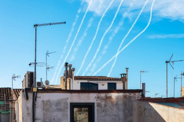 Gökyüzü ve evlerin arka planında birden fazla askeri füzeden duman izi var. Kavram: Füze saldırısı, hava alarmı, Orta Doğu 'da savaş, füze saldırısı, bombardıman.