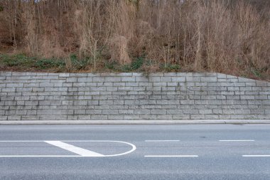 Beyaz yol işaretli eğimli taş duvar ve cadde