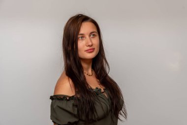 30-35 yaşlarındaki uzun koyu kahverengi saçlı genç bir kadın beyaz arka planda poz veriyor.. 