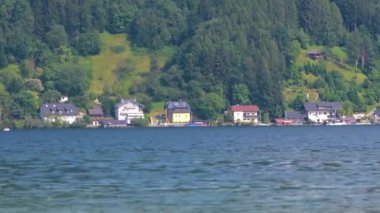 Arka planda Avusturya Alpleri ve evler ve dalgalarla Traunsee Gölü manzarası.