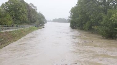 Avusturya 'da bir sel sırasında taşan bir nehrin çalkantılı akışı, yüksek su seviyeleri.