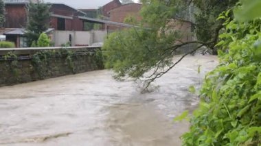 Avusturya 'da bir sel sırasında taşan bir nehrin çalkantılı akışı, yüksek su seviyeleri.