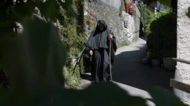 Elinde tespih boncukları ve asası olan siyah cüppeli bir keşiş eski kasabadan geçiyor..