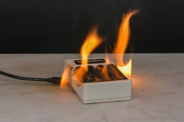 Batarya şarj ünitesi yanıyor, kablolar kıvılcım saçıyor. Kısa devre. Alevler, kıvılcım ve duman.