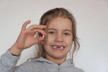 Gevşek dişli bir çocuk onu elinde tutar, mutlu bir gülümseme gösterir.