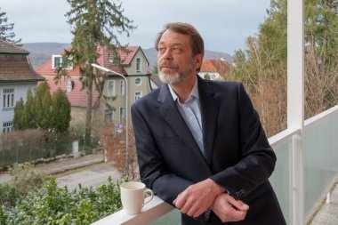 50-55 yaşlarındaki yaşlı bir adam klasik giysiler içinde temiz havanın tadını çıkarıyor.