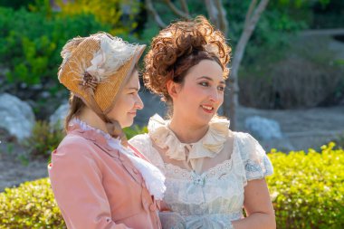 Dönemin kadın konuşmaları tarihi bir bahçenin arka planına karşıdır