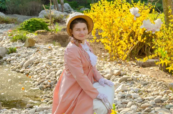 19. yüzyılın başlarında bir kadının romantik portresi çiçek açan bir bahçenin arka planına karşı.