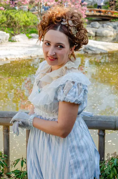 Kadınlık ve bağnazlık: tarihi kostümlü bir kadın resim parkında poz verir.