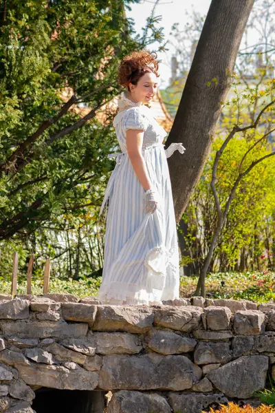 Arka planda çiçek açan bir bahçesi olan, 1800 'lerin başında 35-40 yaşlarında bir kadının manzarası.