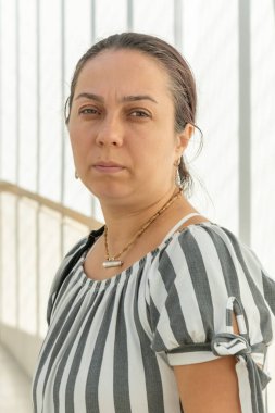 Işığın ve gölgenin geometrik desenine sahip açık renkli bir arkaplanda duran ciddi bir ifadeye sahip bir kadının portresi