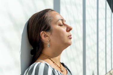 Etnik tarz kıyafetler ve mücevherler içinde sakin ve kendinden emin bir kadın, yakın plan çekilmiş.