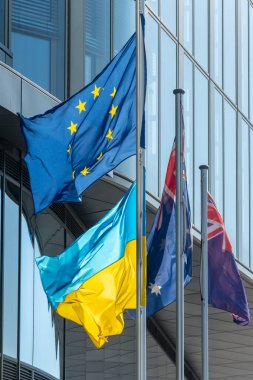 Avrupa Birliği ve Ukrayna 'nın bayrakları rüzgârda cam şehir binalarının zemininde gelişiyor.