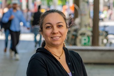 Modern bir metropolün sokaklarını keşfeden gülümseyen bir kadının portresi.