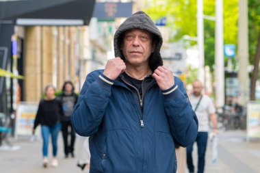 Kapüşonlu bir adam şehir koşuşturmasına karşı modern bir şehir sakinidir.