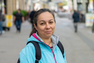 Sırt çantasıyla kameraya bakan kendine güvenen yetişkin bir kadın. Kentsel hareketlilik kavramı.