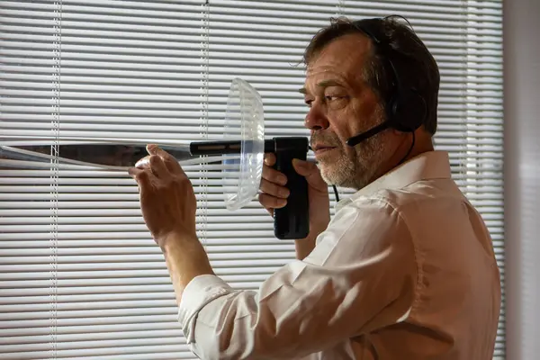 Penceresinde dinleme cihazı olan bir erkek casus. Kulaklık takan bir adam perdelerden yakından izler ve kulak misafiri olmak için yön mikrofonu kullanır.