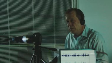 Takım elbiseli bir adam ofis ortamında özel güvenlik kamerası ve ses kayıt cihazı kullanır.