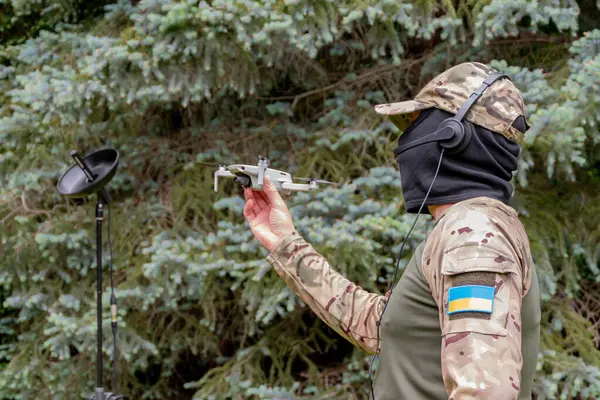 Taktik teçhizat kullanan bir İHA operatörü doğal ortamda bir kuadkopter fırlatır.