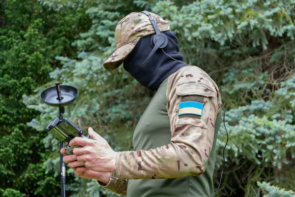 Maske ve kulaklık takan bir Ukraynalı İHA operatörü orman koşullarında çalışır.
