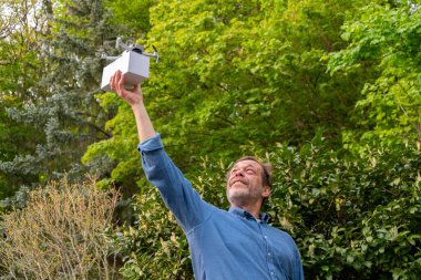 Yeni lojistik çözümler. Yeşillikler arasında yetişkin bir adamın elinde bir dron.