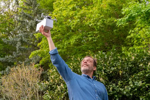 Yeni lojistik çözümler. Yeşillikler arasında yetişkin bir adamın elinde bir dron.