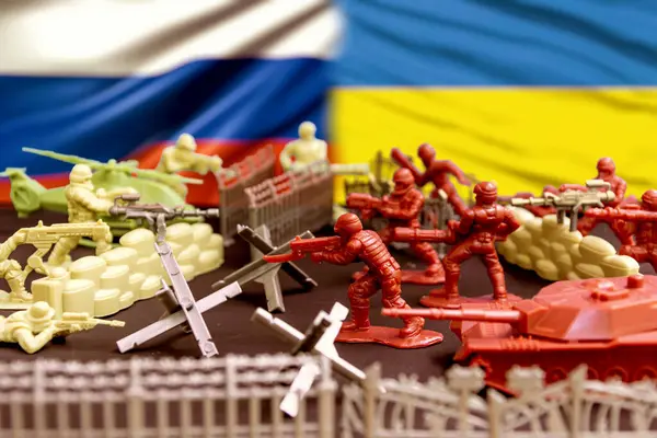 Rus ve Ukrayna bayraklarına karşı savaş. Karşıt taraflardan minyatür askerler barikatlar, bariyerler ve ekipmanlarla çevrili silahlı bir çatışmayı resmediyor