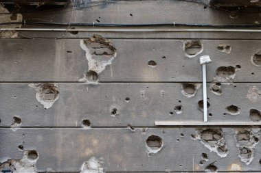 Zaman ve mermilerle delik deşik edilmiş eski bir duvar, gizli geçmişleri ve terk edilmişlik atmosferiyle dolu dramatik bir doku yaratır.