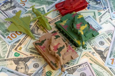 Amerikan askeri harcamalarını finanse ediyor. Oyuncak tanklar, uçak ve helikopter Amerikan dolarlarının arka planında. Savunma bütçesi, askerileştirme ve ordunun mali desteği kavramı