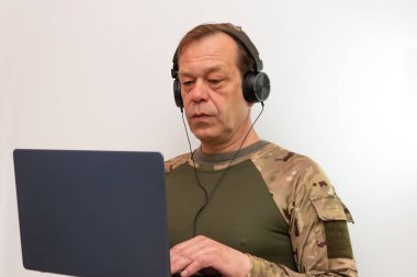 Kulaklık takan bir asker dizüstü bilgisayar kullanmaya odaklanır - online öğrenme, takım iletişimi veya keşif kavramı