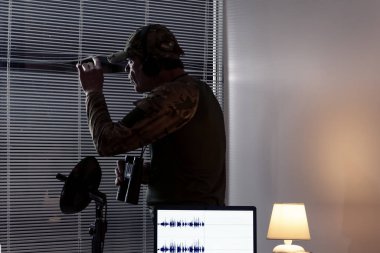 İçerideki izleme sürecinde bir gözlemci ya da analist: laptop, mikrofon, kamera, dürbün