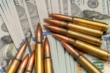 Cephane ve Amerikan doları. Kompozisyon, silahlar, güç ve para arasındaki ilişkiyi vurguluyor.