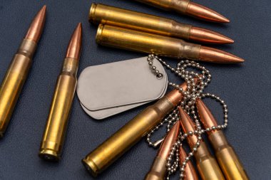 Cephaneye yakın çekim ve iki metal ordu rozeti. Kompozisyon, silahlı kuvvetler ve gazilerin temalarını aktarıyor.