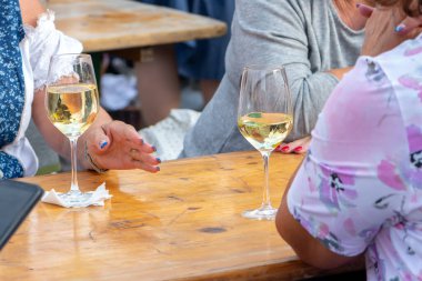 Kadınlar Retz 'deki bir şarap festivalinde tahta masada beyaz şarapla sohbet ediyorlar.