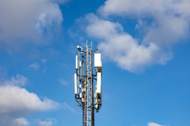 Two telecommunication towers with 4G, 5G transmitters. Cellular base stations with transmitting antennas on a telecommunication tower on a background of blue sky with pink-yellow clouds. Tinted. High