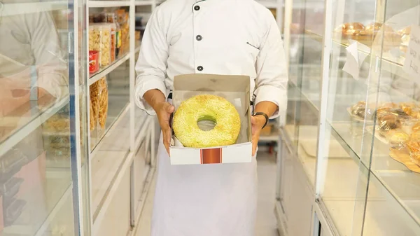 bakery chef holding cake in bakery shop, confectionery concept