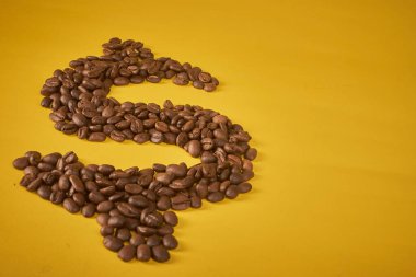 Kahve çekirdekleri dolar şeklinde ve üzerinde sarı arkaplanda 