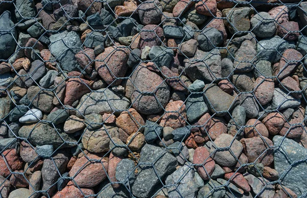 金属丝网中的大石头有不同的颜色 — 图库照片