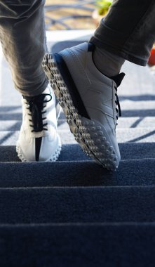                                Adamın ayağında beyaz spor ayakkabıları var.