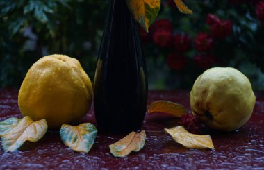                      Ayva ve yapraklar masanın üstünde, bir damla su meyvenin üzerinde.