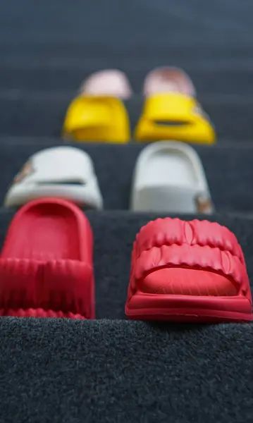 Different types of rubber shoes stand on the carpet