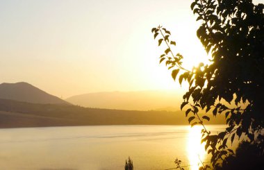                                 Gün batımında, göl ve evler dağın eteklerinde görülebilir.