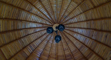                                Siyah bir avize ahşap bir direğe asılı.