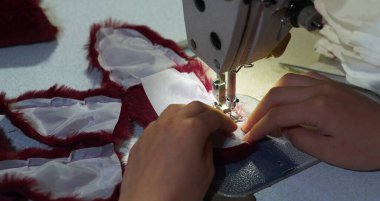                                Terzi kadının eli dikiş makinesine kabarık kumaş dikiyor.