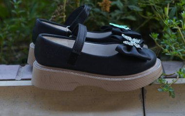                                Siyah ayakkabılı, fiyonklu kızlar doğada ayakta durur.