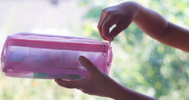                     Bir kızın eli pembe bir kalem kutusunu açıyor.           