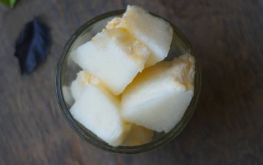                                 Masanın üzerinde kristal bir kasede dilimlenmiş bir kavun var..